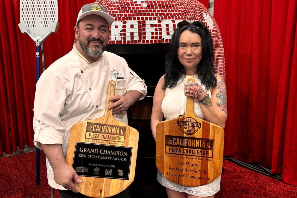 This photo shows Giovanni Labbate holding his Grand Champion pizza peel from the California Pizza Challenge. Next to him is his wife holding up another peel for 1st place in the 3-Cheese Championship.