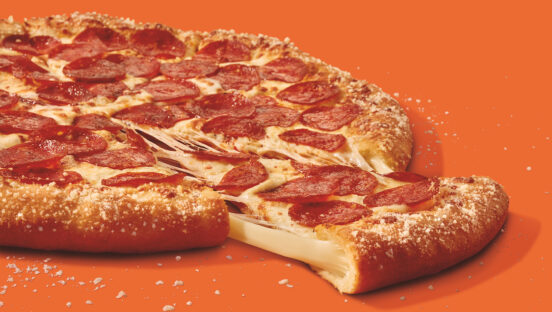 This photo shows a whole stuffed-crust pizza with one slice pulled out.