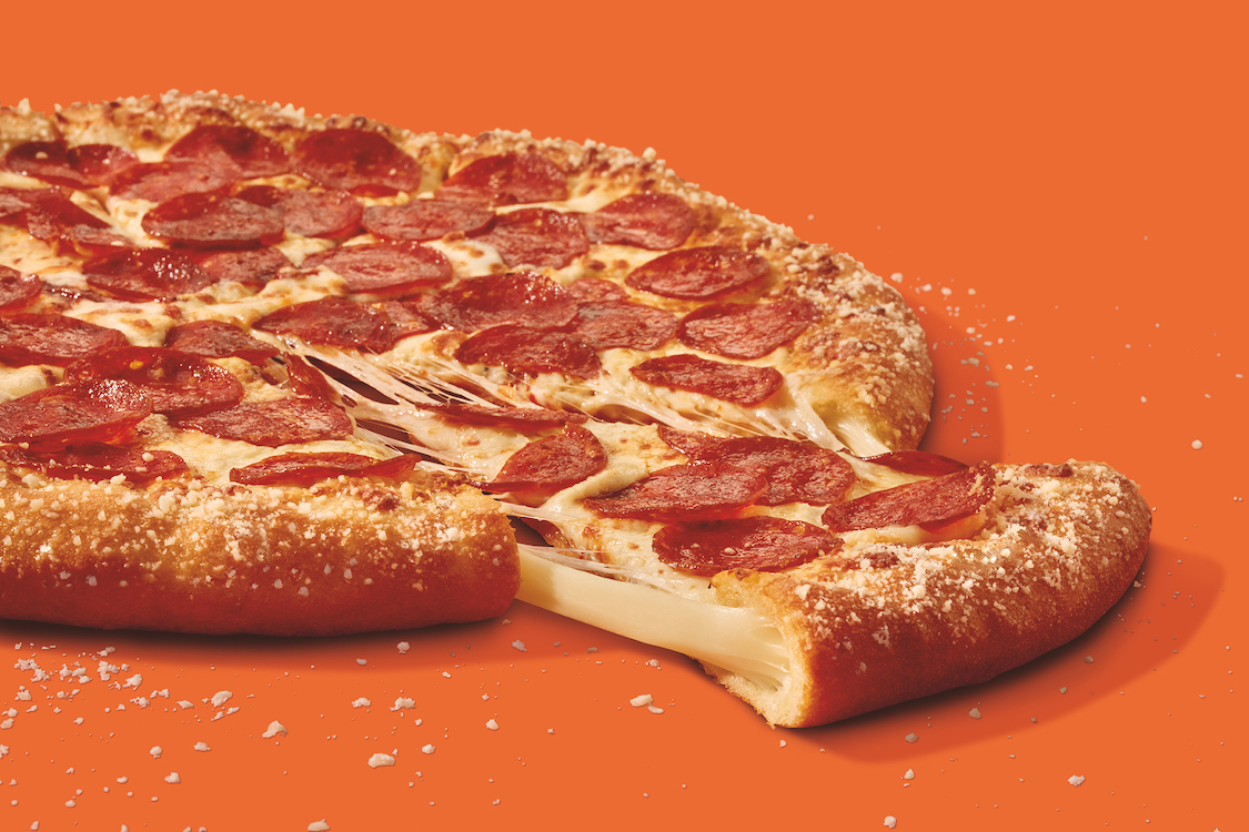 This photo shows a whole stuffed-crust pizza with one slice pulled out.