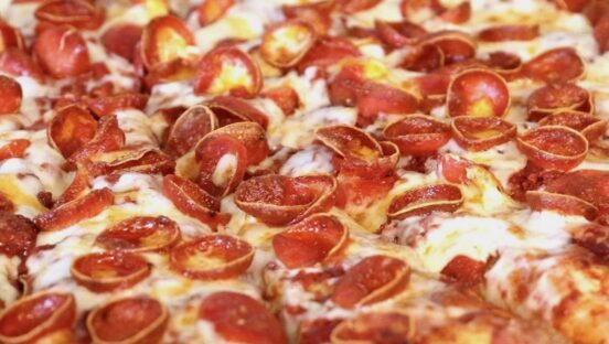 This photo shows a close-up of a pizza topped with mozzarella and cupped pepperoni slices.