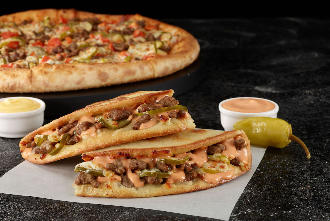 This photo shows a pair of Papa John's Papadillas with a regular pizza in the background.