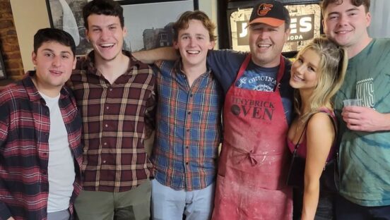 This photo shows the owner of Tiny Brick Oven with a group of young customers.