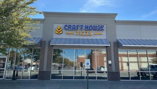 This photo shows the exterior of a Craft House Pizza location against a bright blue sky.