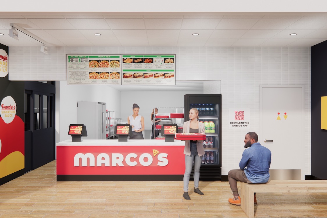 This photo shows a woman holding a pizza carryout box in front of the counter at a Marco's Pizza location.