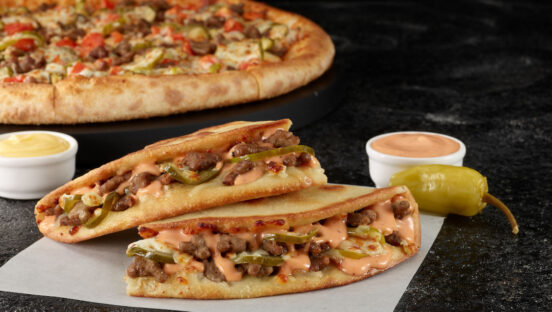 This photo shows two Papa Johns' Papadillas in the foreground and a Double Cheeseburger pizza in the background.