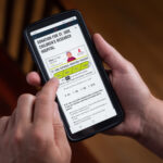 This photo shows a person's hands holding a smartphone with Domino's ordering screen, inviting customers to donate to St. Jude Children's Research Hospital.