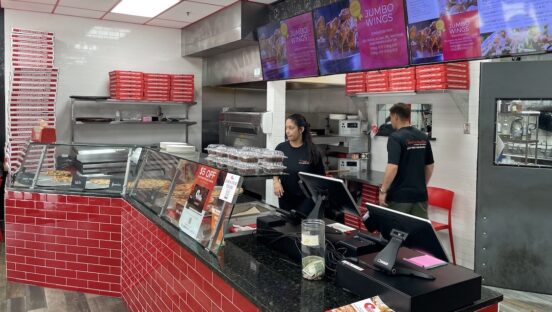 This photo shows employees behind the counter at a Cannoli Kitchen Pizza location.