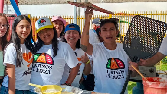This photo shows a group of young Ecuadorians wearing Latinos en Pizza t-shirts at the festival. One boy is spinning pizza dough.