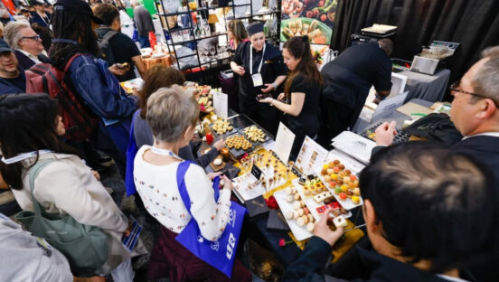 This photo shows New York Restaurant Show attendees crowded around a booth featuring pastries.