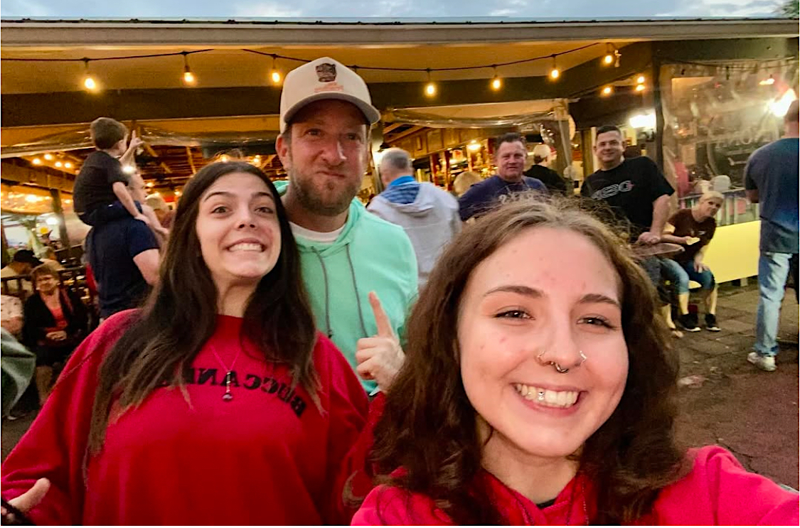 This photo shows Dave Portnoy with two young women dressed in red at The NONA Slice House.