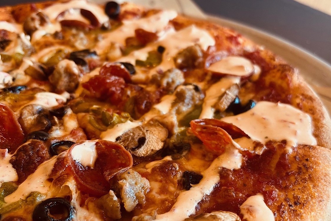 This photo shows a close-up of a pizza topped with the Spicy Ranch sauce.