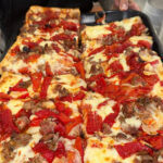 This photo shows a Pan-Fried Sicilian pizza topped with sausage and roasted red peppers.