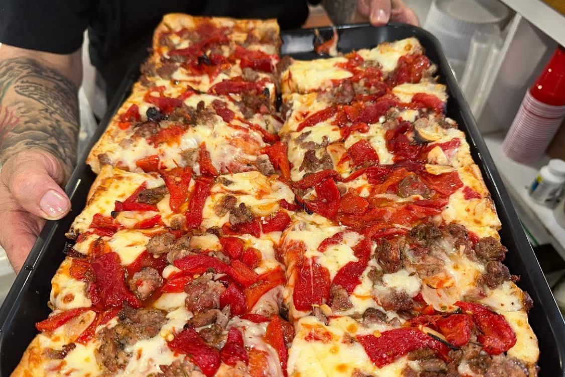 This photo shows a Pan-Fried Sicilian pizza topped with sausage and roasted red peppers.