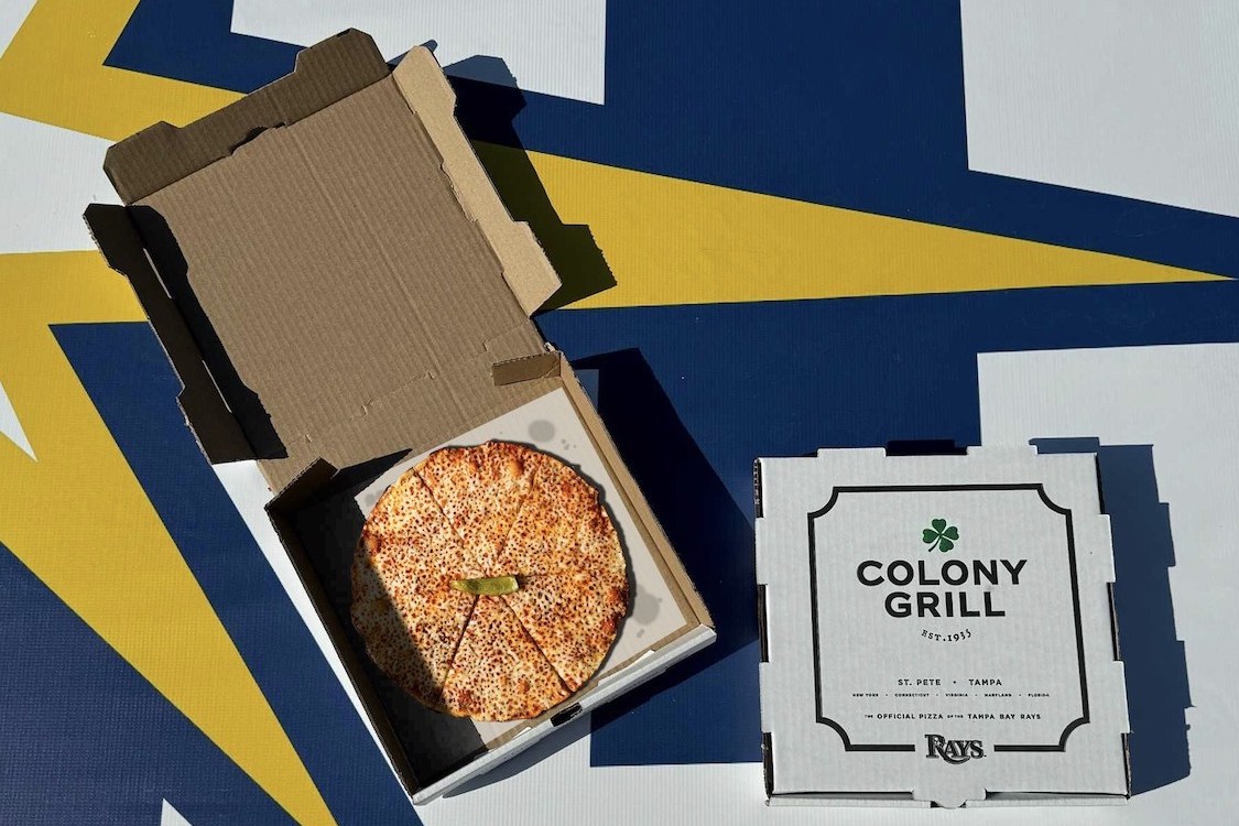 This photo shows a hot oil bar pie in an open box, next to a closed box with the Colony Grill logo.