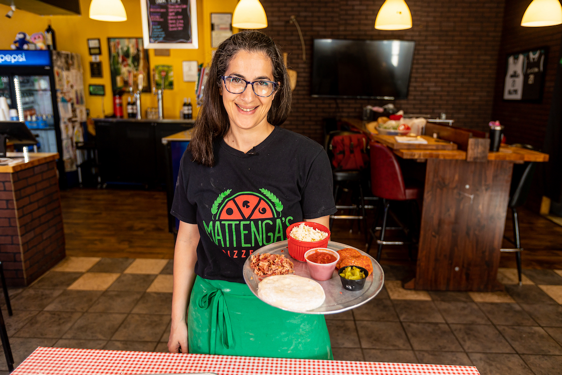 This photo shows Hengam Stanfield standing in one of her restaurants' dining room and holding a platter of appetizers.