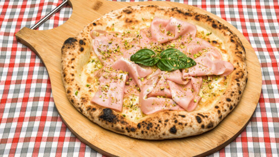 This photo shows a pizza with a blistered crust and topped with slices of mortadella.