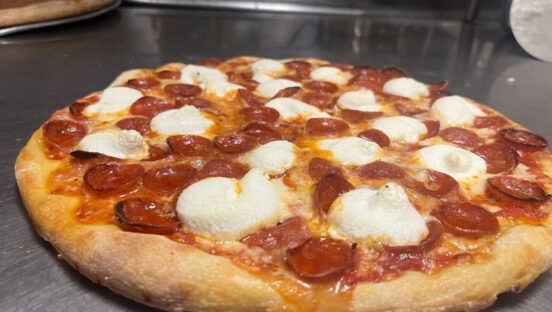 This photo shows a pizza from Patelmo's that's topped with cup-and-char pepperoni, ricotta and a hot honey drizzle.