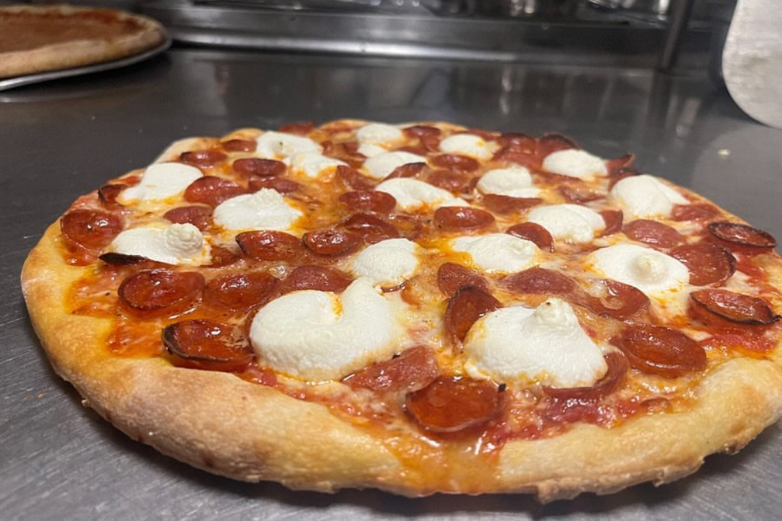 This photo shows a pizza from Patelmo's that's topped with cup-and-char pepperoni, ricotta and a hot honey drizzle.