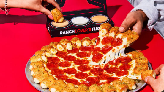 This photo shows customers' hands removing pieces of the Cheesy Bites Pizza topped with pepperoni.