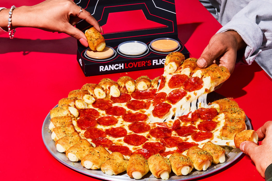 This photo shows customers' hands removing pieces of the Cheesy Bites Pizza topped with pepperoni.