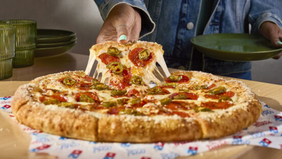 This photo shows a woman's hand pulling a slice of stuffed crust pizza with a great cheese pull.