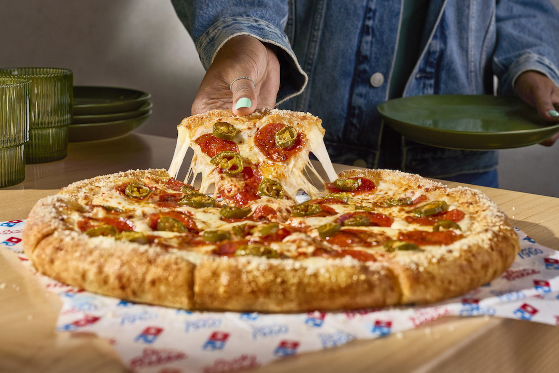 This photo shows a woman's hand pulling a slice of stuffed crust pizza with a great cheese pull.
