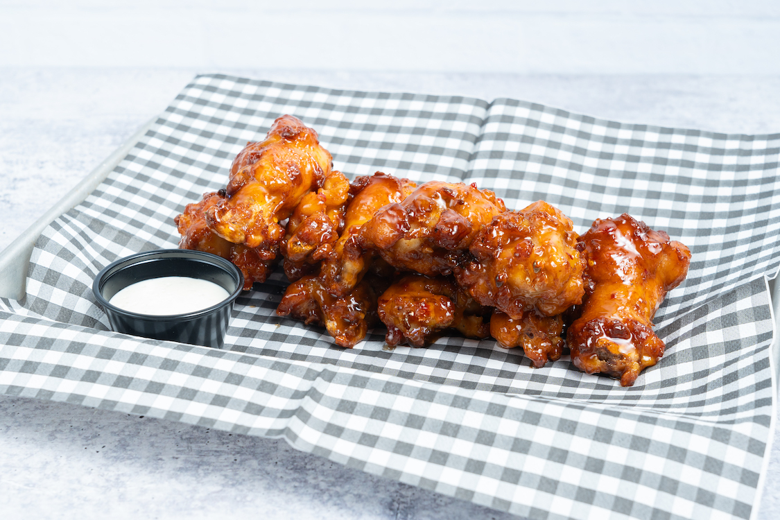 This photo shows a plate containing six oven-roasted chicken wings and Ranch dipping sauce.