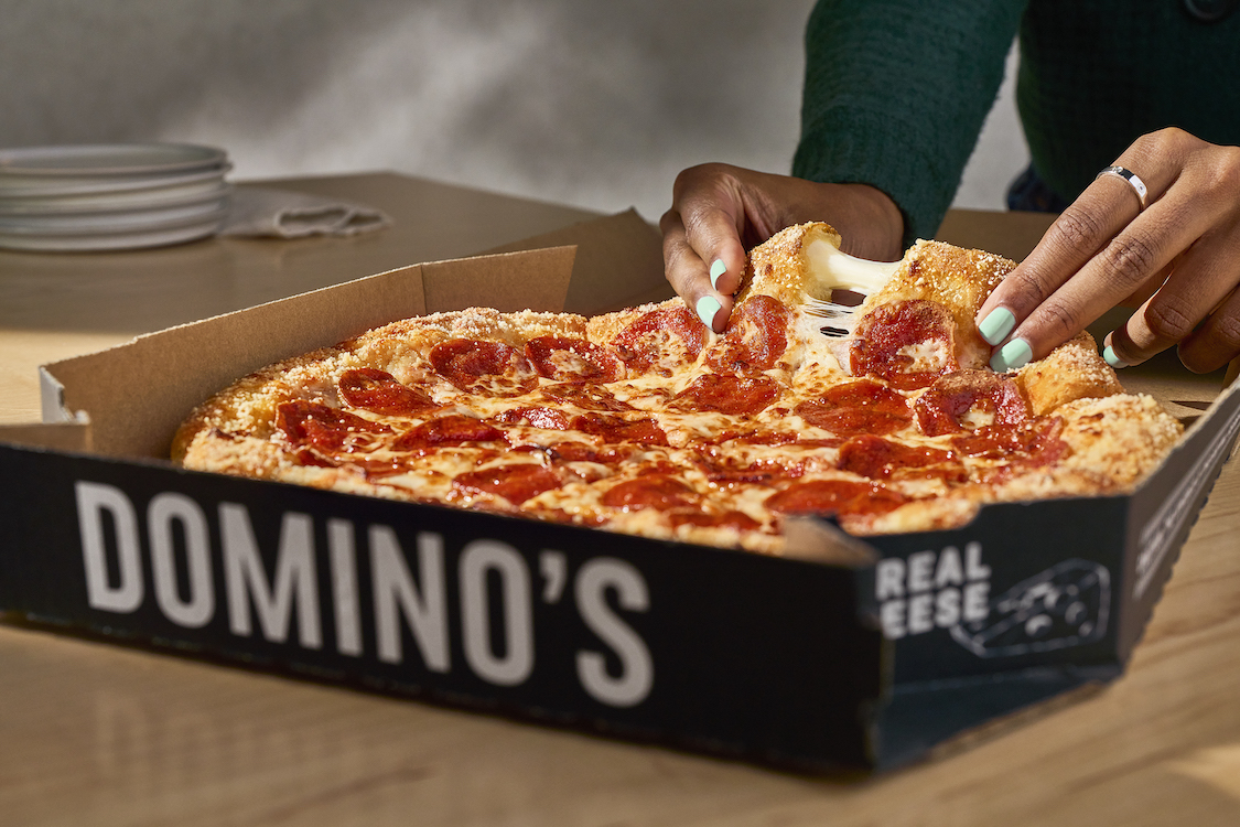 This photo shows a cheese pull from a slice of Domino's Parmesan Stuffed Crust pizza.
