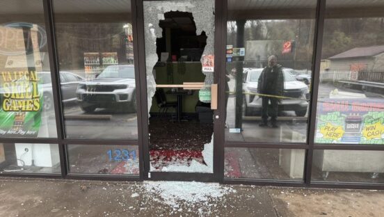 This photo shows the smashed entrance to Fellini's Pizzeria, with a pile of broken glass in the front.