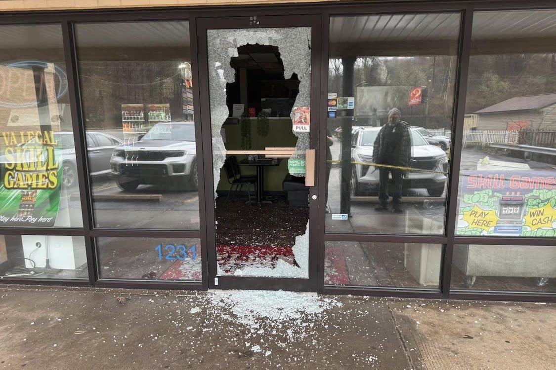 This photo shows the smashed entrance to Fellini's Pizzeria, with a pile of broken glass in the front.
