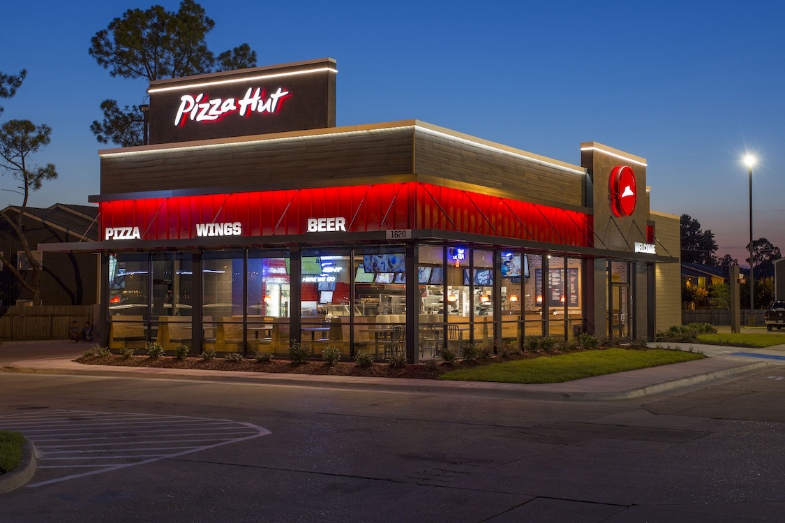 This photo shows the exterior of a Pizza Hut restaurant against a dark-blue sky.