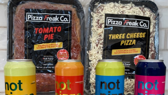 This photo shows Pizza Freak Co.'s packaged Three Cheese Pizza and Tomato Pie with several canned beverages lined up in front of them.