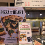 This photo shows a copy of "Pizza From the Heart" and signage promoting the book on the counter at Paulie Gee's Soul City Slice.