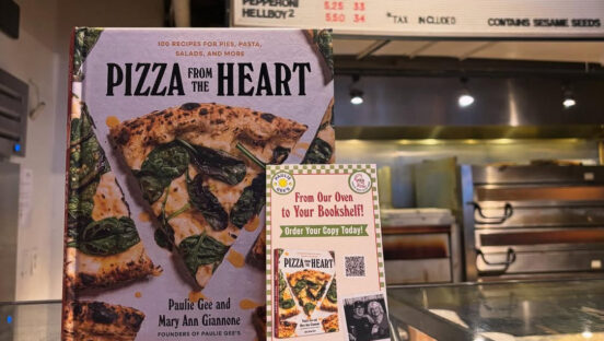 This photo shows a copy of "Pizza From the Heart" and signage promoting the book on the counter at Paulie Gee's Soul City Slice.