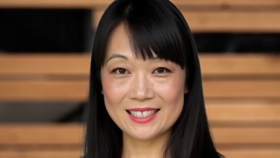 This photo shows a smiling Jaimie Lowe from the neck up with shoulder-length black hair.