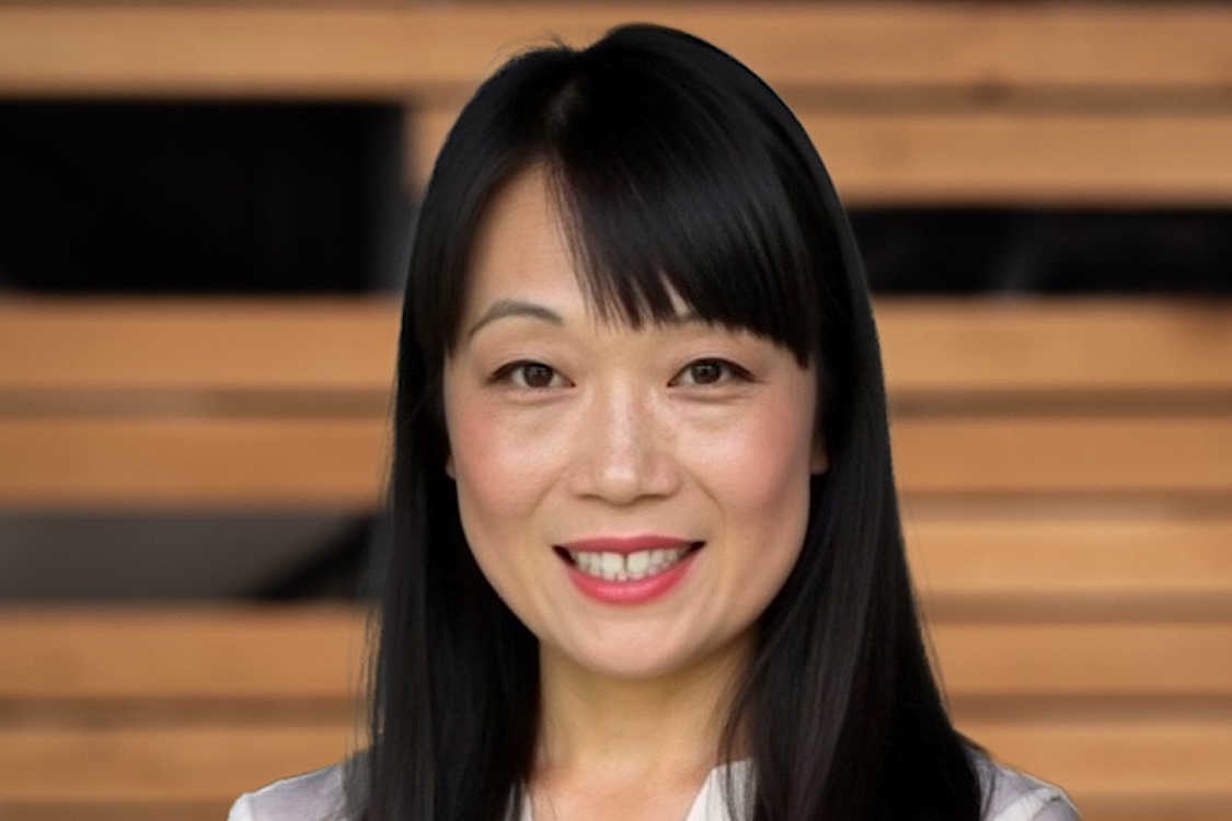 This photo shows a smiling Jaimie Lowe from the neck up with shoulder-length black hair.