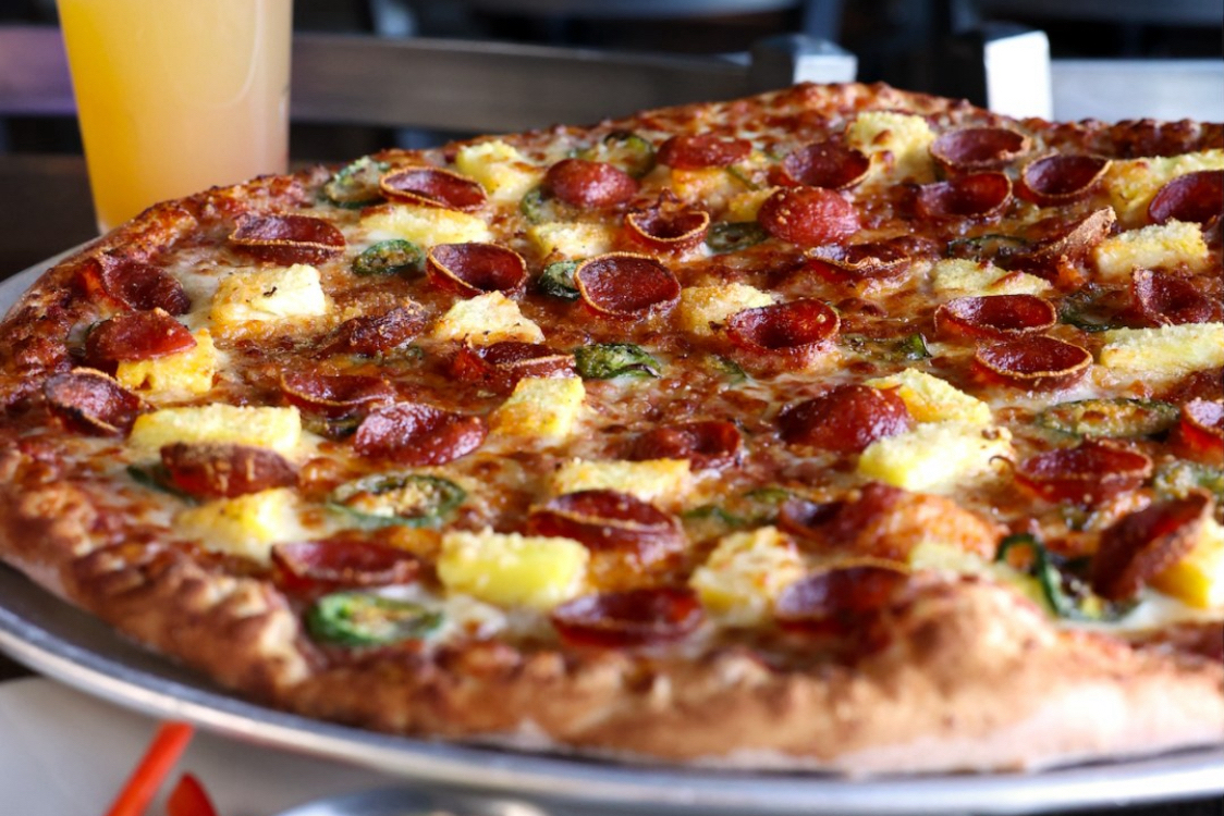 This photo shows a pizza topped with pepperoni, jalapeños and pineapple.