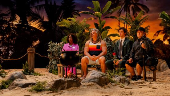 This photo shows three Pretzel Crust Island competitors plus a crew member seated on a bench together, with a faux tropical island setting behind them. They're all staring off-camera and looking a little nervous.