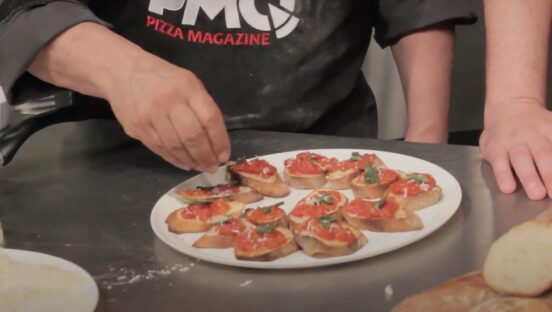 This photo shows John Arena's hands sprinkling cheese on bruschetta.