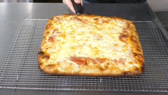 This photo shows a cheesy pan-fried Sicilian pizza fresh out of the oven.