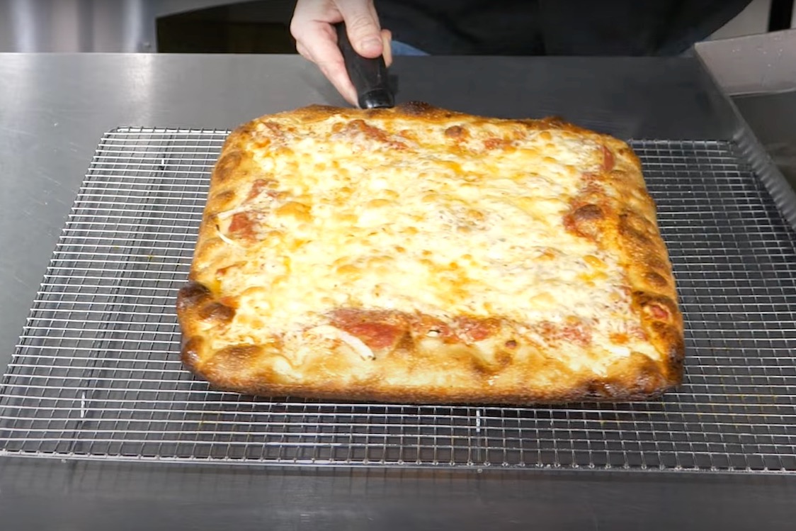 This photo shows a cheesy pan-fried Sicilian pizza fresh out of the oven.