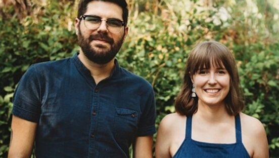 This photo shows the two owners of Pizza Verde standing in front of some greenery.