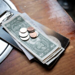 This shows tip money left on a restaurant table, including $1 bills and change.