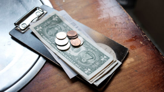 This shows tip money left on a restaurant table, including $1 bills and change.