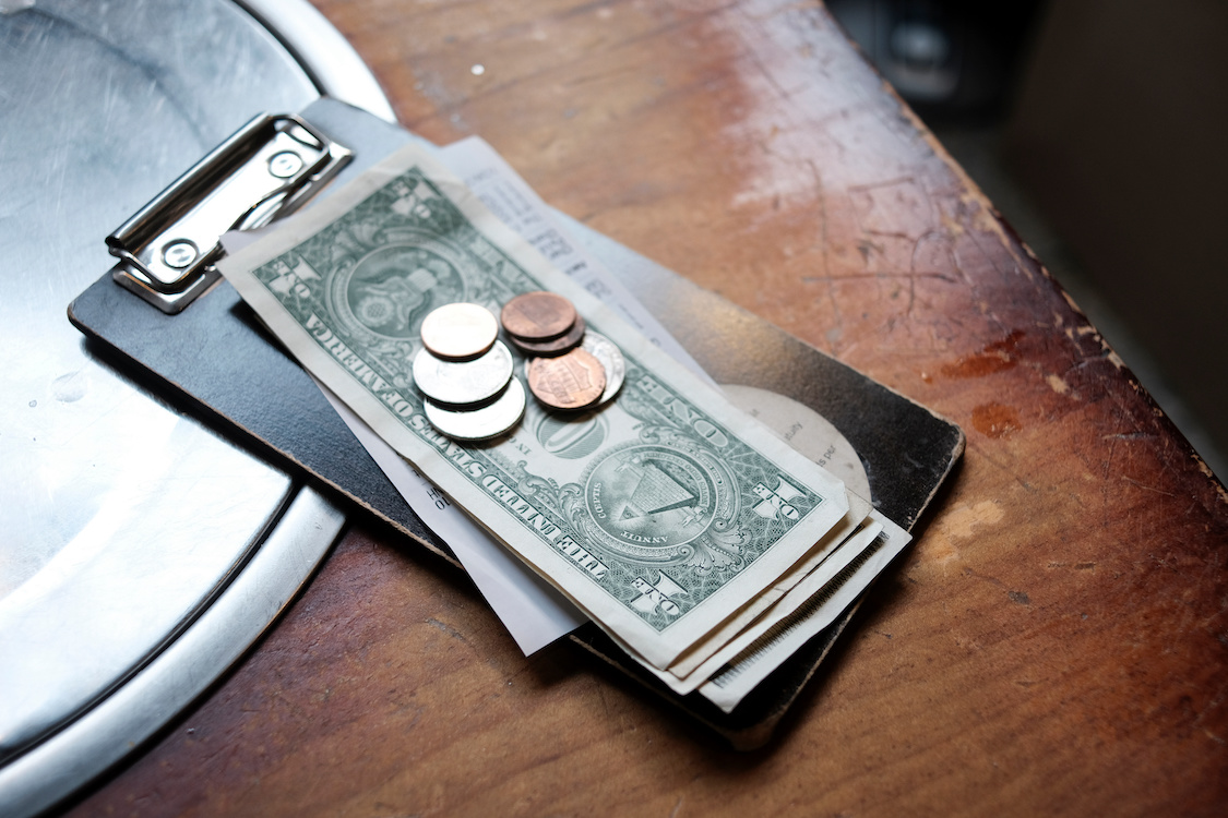 This shows tip money left on a restaurant table, including $1 bills and change.