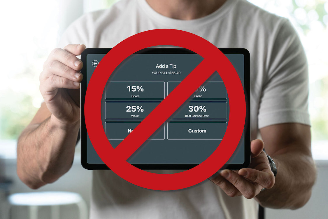This photo shows a man in a white T-shirt holding a tip screen in front of him, but there's a big red circle with a diagonal line running through it to suggest "no tips required."