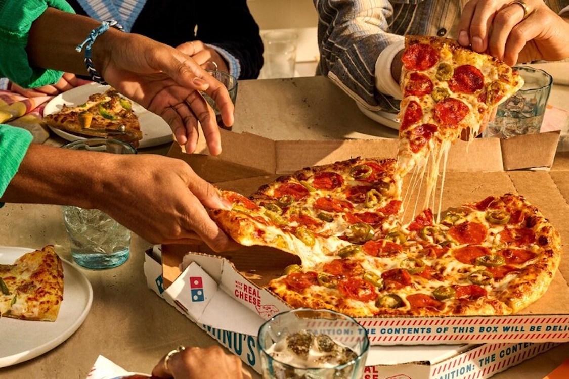 This photo shows customers' hands as they pull out slices of a pepperoni pizza.