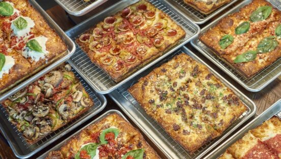 This photo shows a wide variety of Detroit-style pizzas offered by Emmy Squared Pizza.