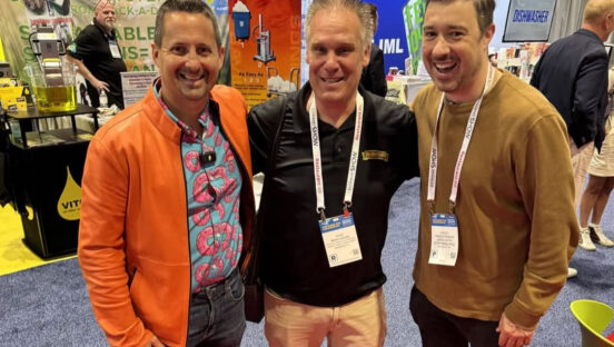 This photo shows Matt Plapp with Brian Weevel and PMQ's Charlie Pogacar, all smiling with their arms around each other, on the floor of the National Restaurant Association Show.
