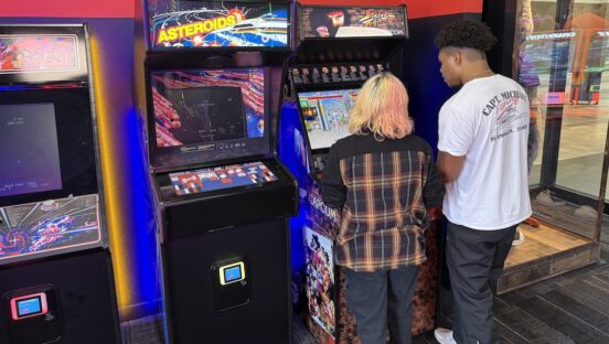 This photo shows a young man and a young woman playing a Street Fighter game next to an Asteroids machine from the early 1980s.